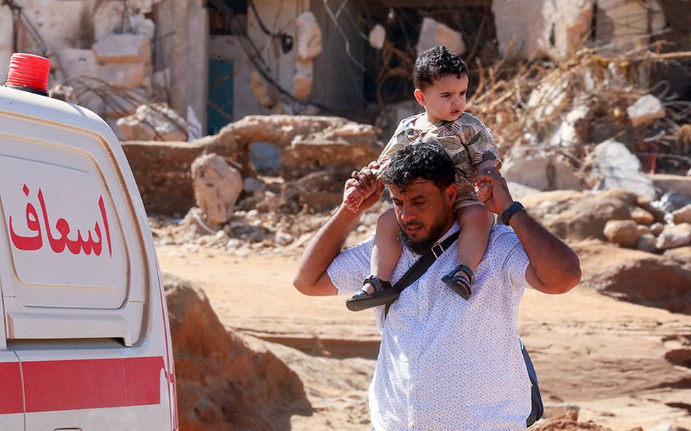 Libyen Überschwemmungen: Ein Mann trägt im Überschwemmungsgebiet einen Jungen auf den Schultern.