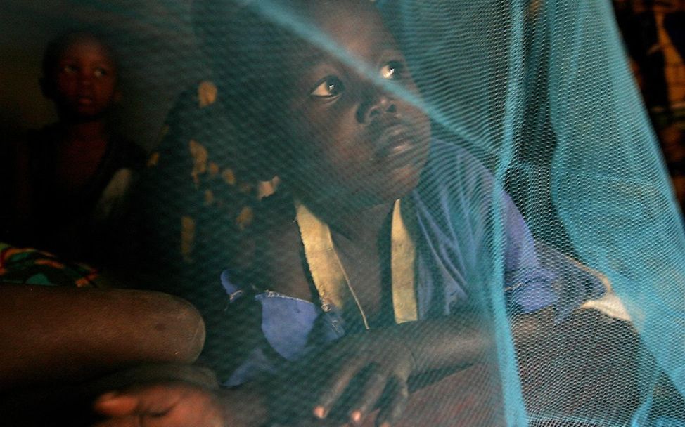 Zentralafrika: Ein Kind sitzt geschützt unter einem von UNICEF ausgegebenen Moskitonetz. © UNICEF/Pierre Holtz 