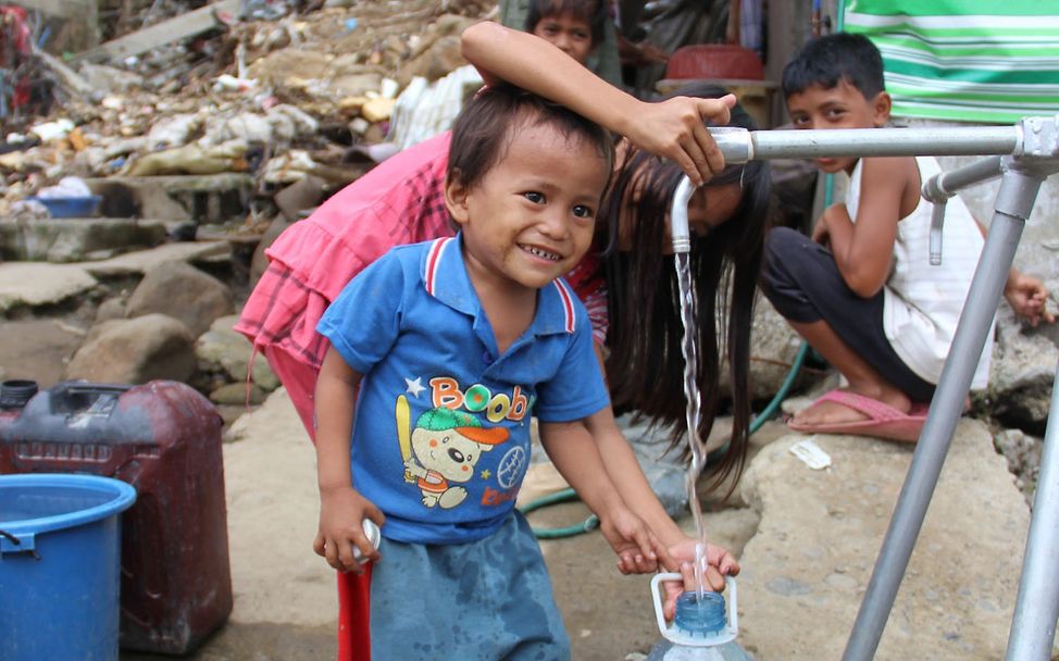 Junge von den Philippinen beim Abfüllen von Wasser. © Louise Lane