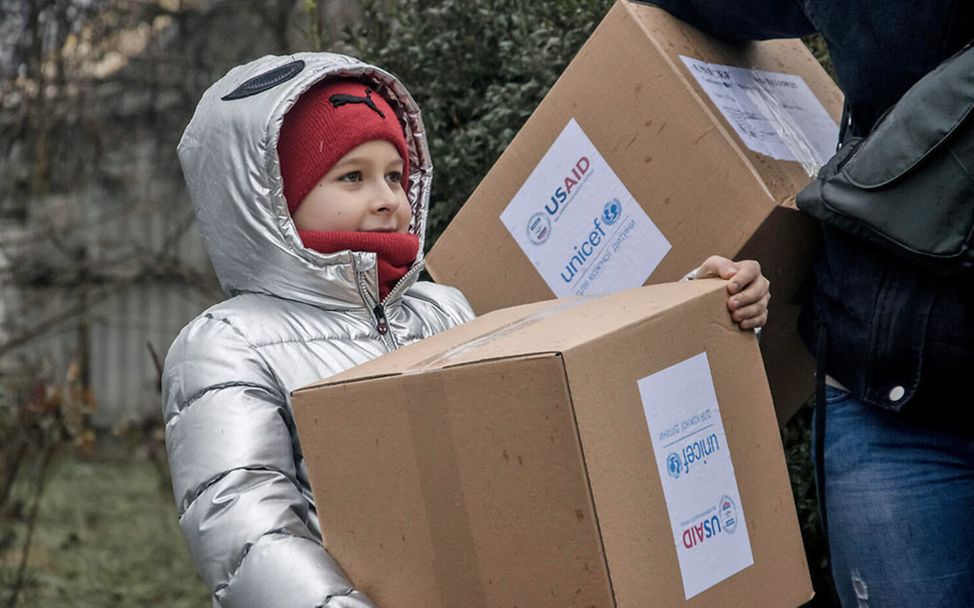 Ukraine Krieg Nothilfe: Ein Mädchen bekommt von UNICEF einen Karton mit Winterkleidung