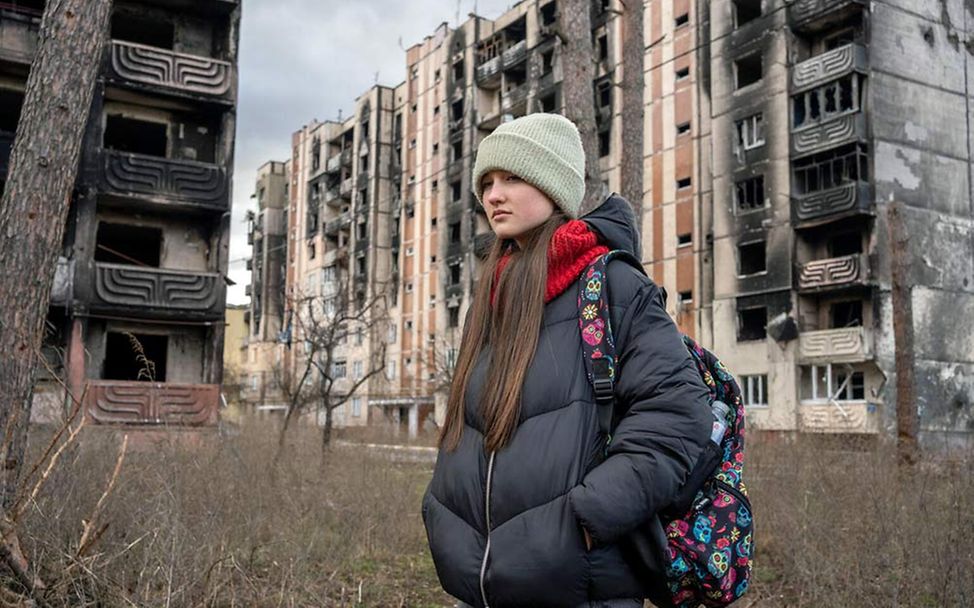 Ukraine Nothilfe: Ein Mädchen läuft durch eine zerbombte Häuserlandschaft. 