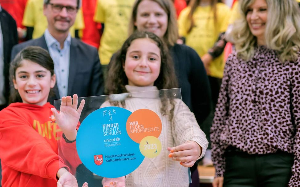 Zwei Grundschülerinnen in Salzgitter nehmen die Auszeichnung zur Kinderrechteschule entgegen. 