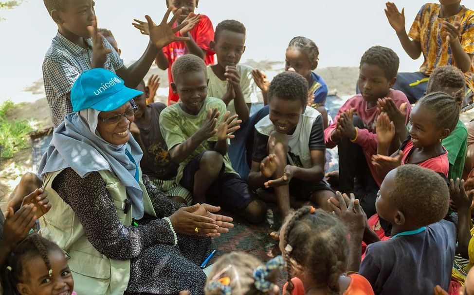 Eine UNICEF-Kinderschutzexpertin spielt mit einer Gruppe von sudanesischen Kindern 