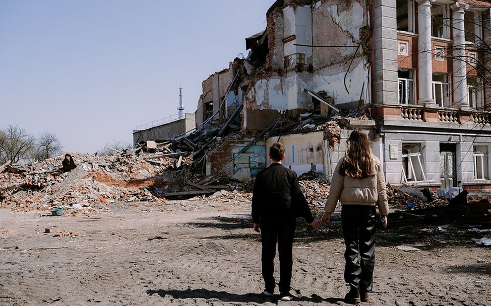Ukraine: Die Geschwister Anastasia (17) und Mykhailo (12) stehen vor ihrer zerstörten Schule.