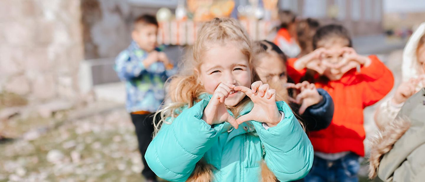 Armenien: Ein Mädchen lächelt und bildet mit ihren Händen ein Herz.