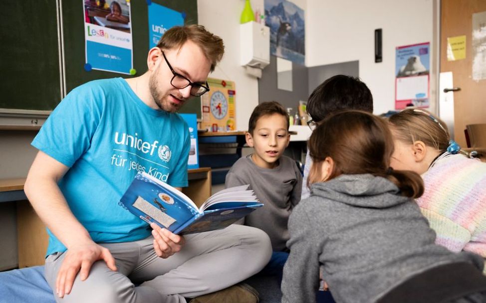 Ehrenamtlich Engagierter liest gemeinsam mit den Schulkindern.