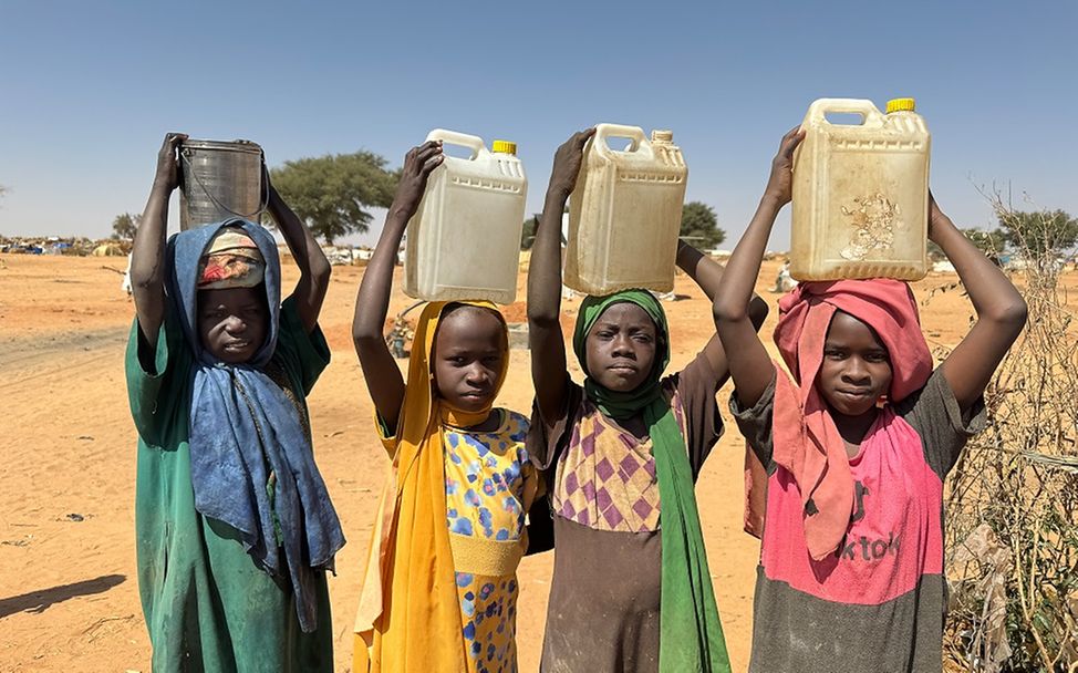 Eine Gruppe von Kindern in einem Flüchtlingscamp im Tschad trägt Wassereimer.