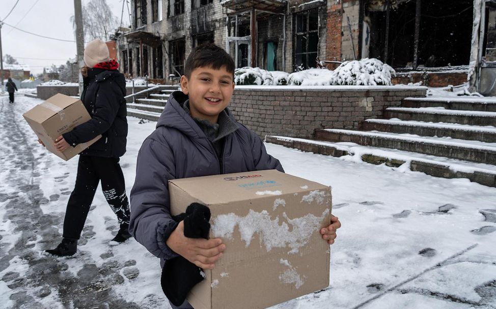 Ukraine Krieg Nothilfe: Ein Junge im Osten des Landes trägt einen UNICEF-Karton mit Hilfsgütern. 