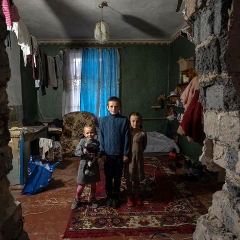 Jahrestag Ukraine-Krieg: Ukrainische Kinder stehen in ihrem zerstörten Haus.