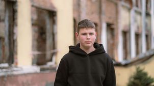 Jahrestag Ukraine-Krieg: Junge steht vor seiner zerstörten Schule 