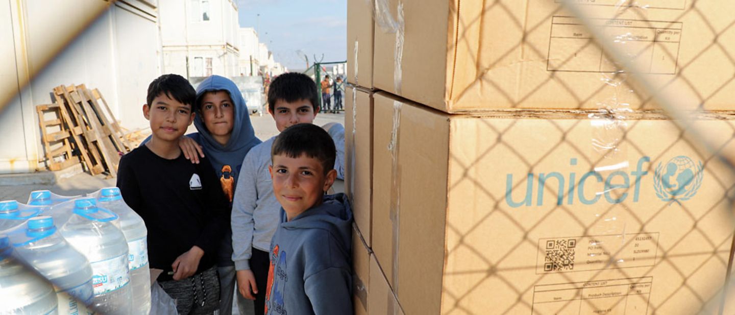 Spenden Türkei: Kinder in der Türkei stehen nach dem Erdbeben 2023 neben UNICEF-Hilfsgütern