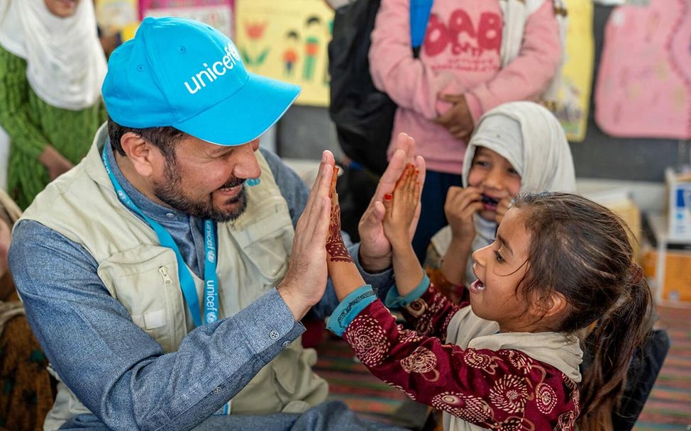 Spenden Afghanistan: Ein Mädchen und ein UNICEF-Mitarbeiter spielen fröhlich miteinander. 
