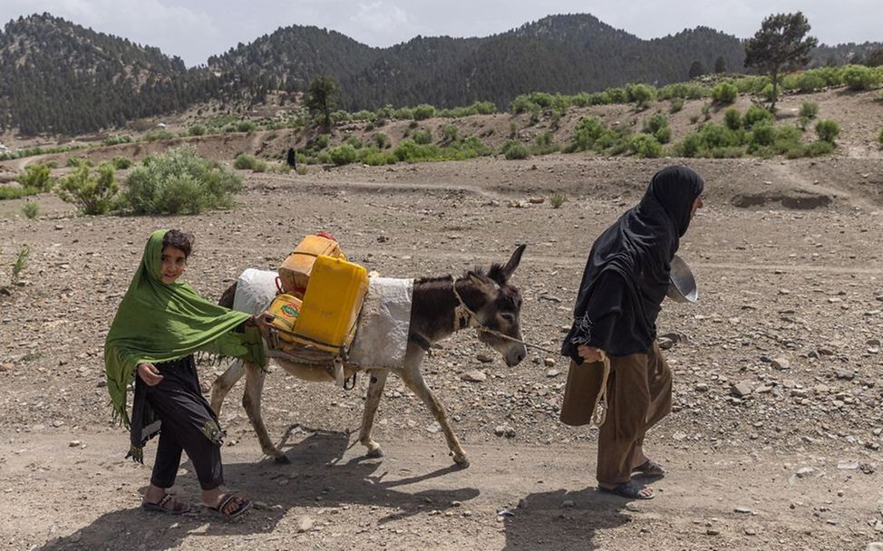Noorbala (6) holt mit Großmutter und Esel Wasser in Kan Rozi Khel, Afghanistan. 