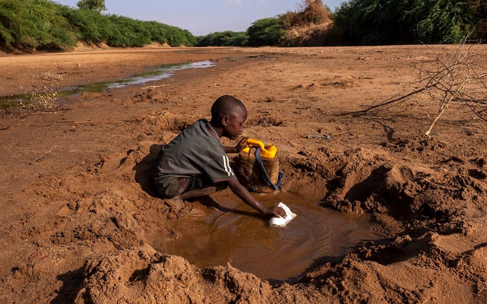 Somalia: Junge sammelt Wasser in einer Pfütze.