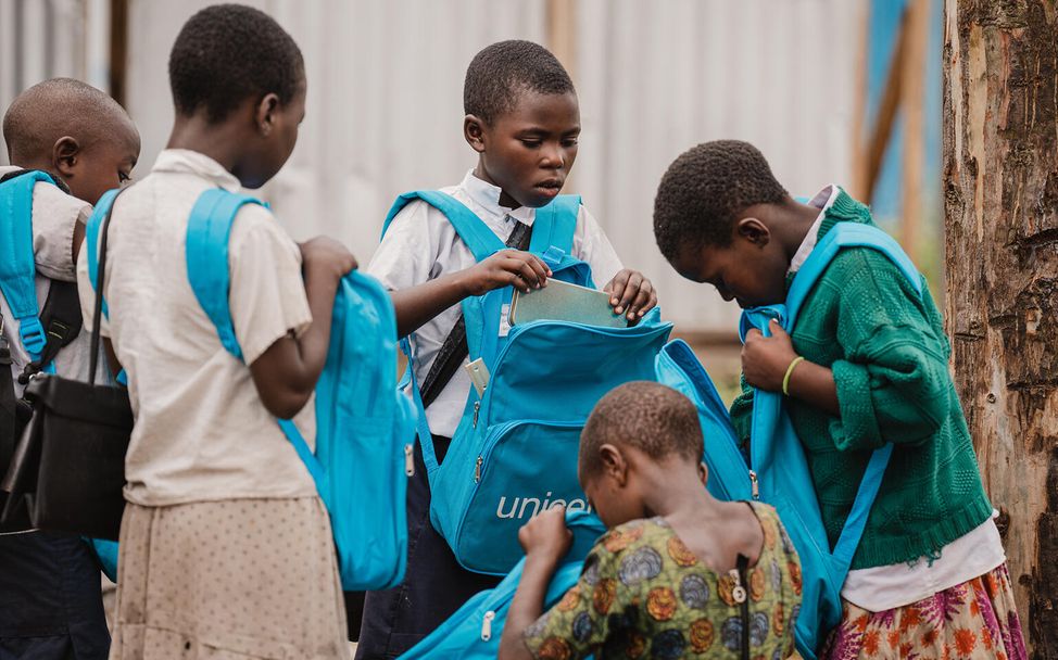 Gruppe Schüler*innen begutachten neue Schultaschen von UNICEF.