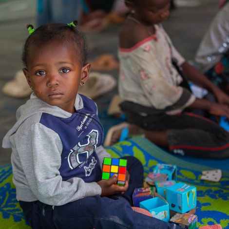 Sudan: Kind spielt mit Zauberwürfel auf dem Boden