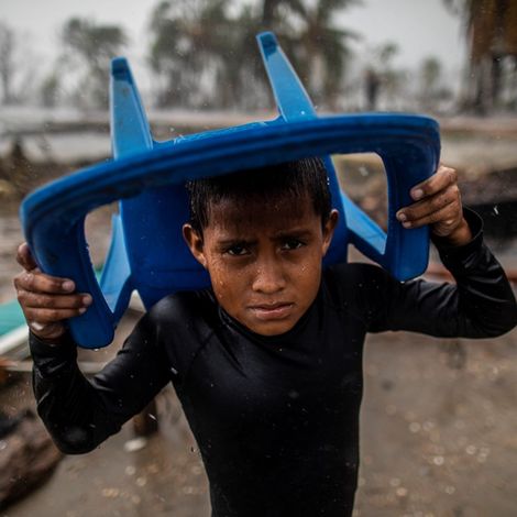 Nicaragua: Junge sucht Schutz unter einem Plastikstuhl.