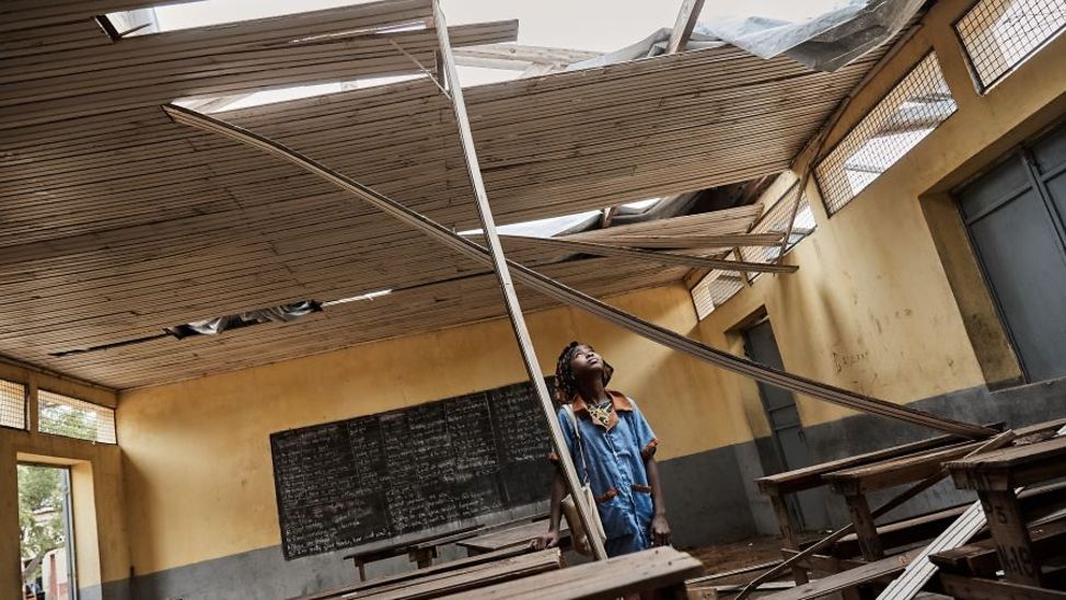 Kind steht in durch Sturm zerstörten Schulgebäude.