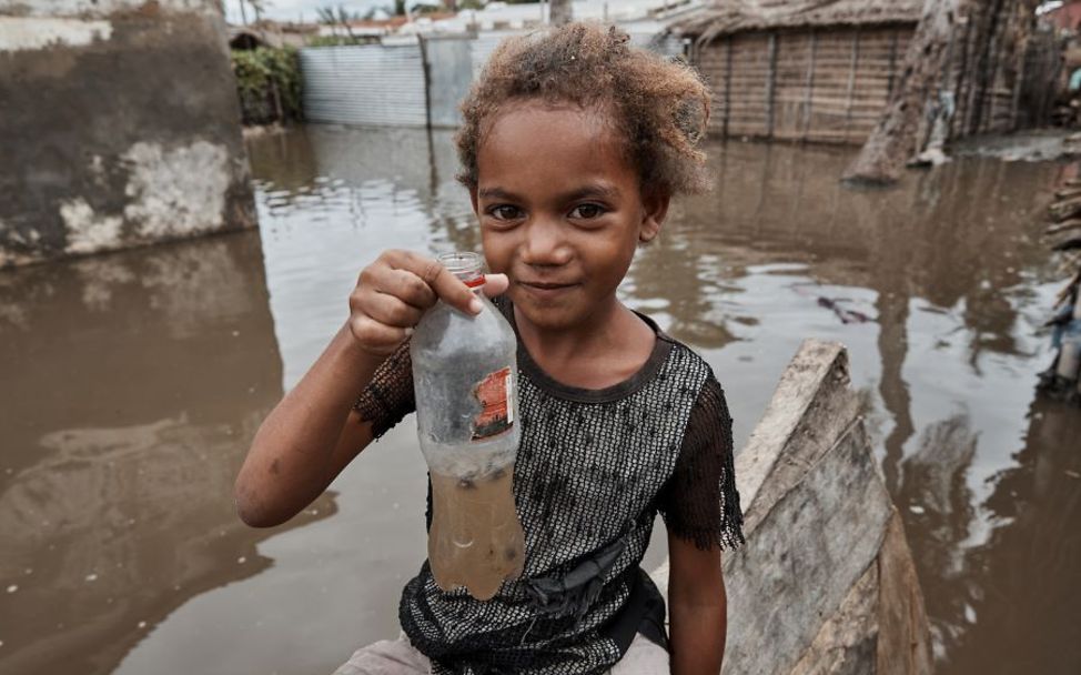 Mädchen hält eine Flasche mit verschmutztem Wasser in der Hand.