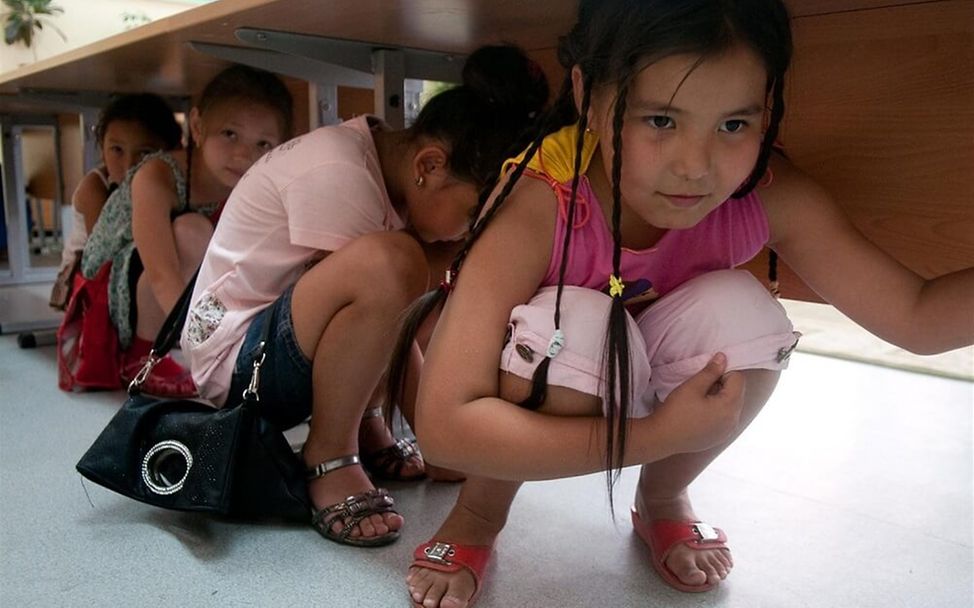 Erdbeben in Kasachstan: Schülerinnen üben, sich unter einem Tisch in Sicherheit zu bringen