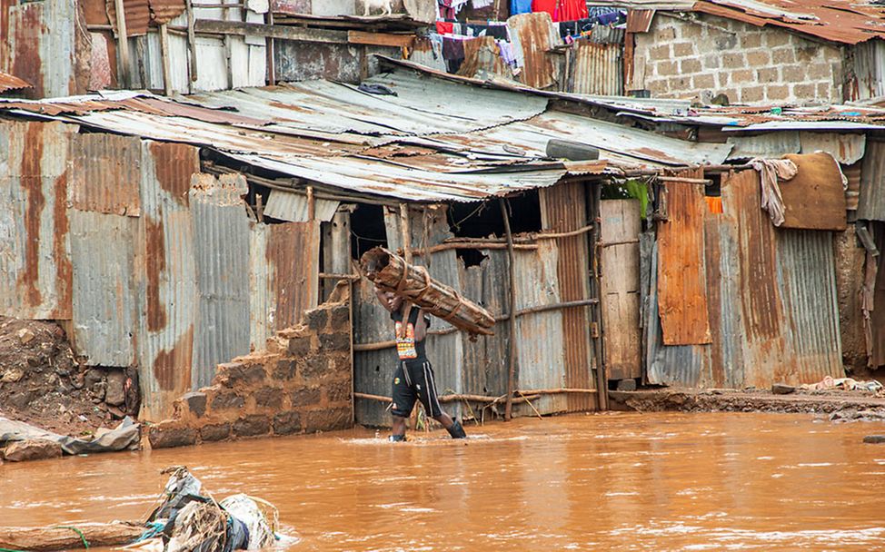El Niño 2024: In Nairobi watet nach den schweren Überschwemmungen ein Mann durchs Wasser. 