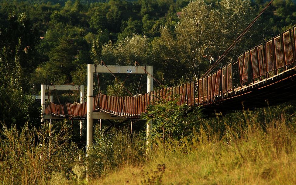 Eine rostige Hängebrücke mit Holzbohlen führt nach Rusavatu. | © UNICEF/Tarneden