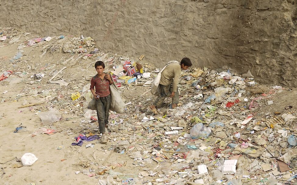 Zwei Jungen sammeln in einem ausgetrockneten Flussbett Abfall, um diesen anschließend wiederzuverwerten. ©UNICEF/von Welser