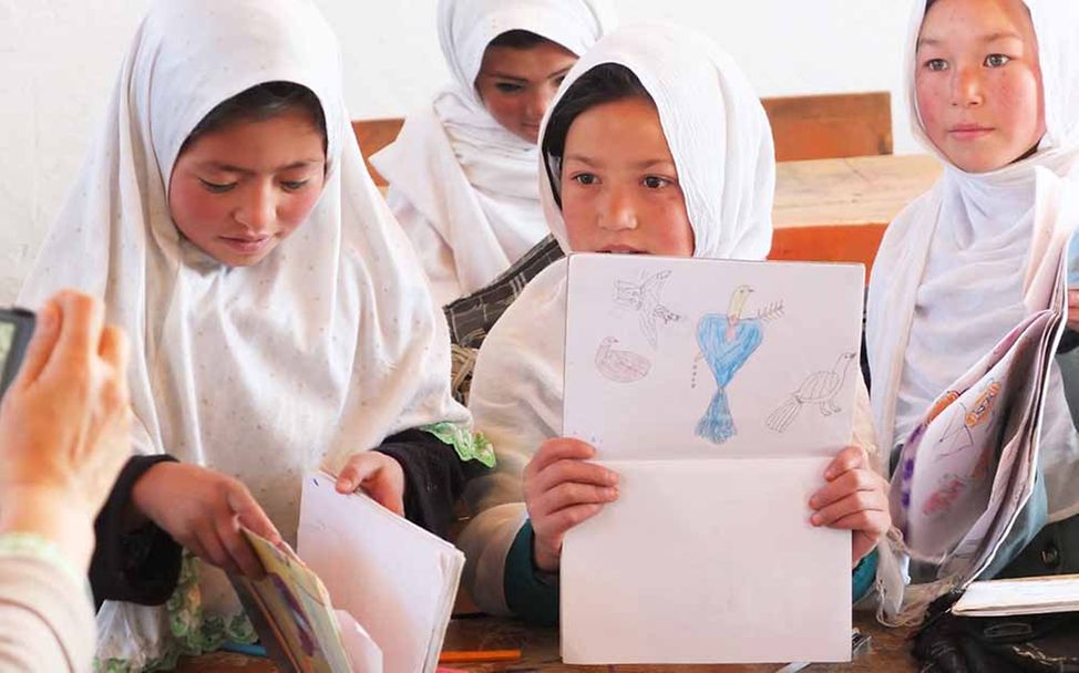 Afghanistan: Mädchen zeigen auf ihren Bildern, was sie gemalt haben. 