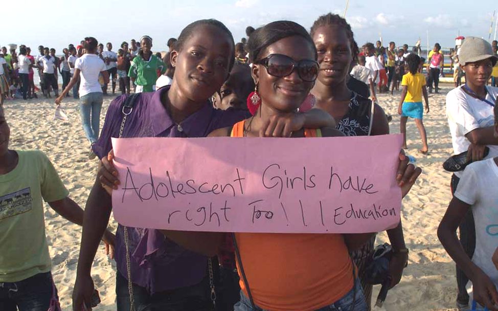 Liberia Let us learn: Zwei jugendliche Mädchen halten ein Plakat für Mädchenrechte hoch. 